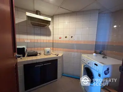 Cozy kitchen with washing machine and tiled walls, featuring a compact layout ideal for efficient use of space.