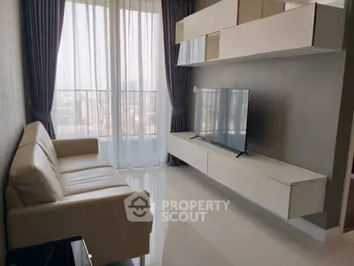 Modern living room with sleek furniture and large window offering natural light.