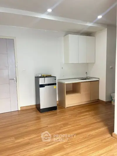 Modern minimalist kitchen with wooden flooring and compact layout.