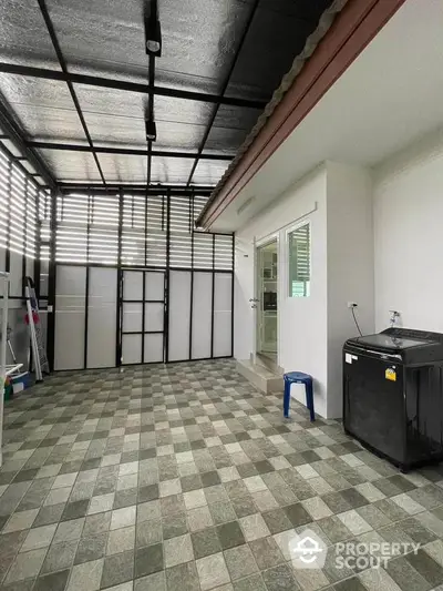 Spacious tiled patio with modern washing machine and sliding door access.