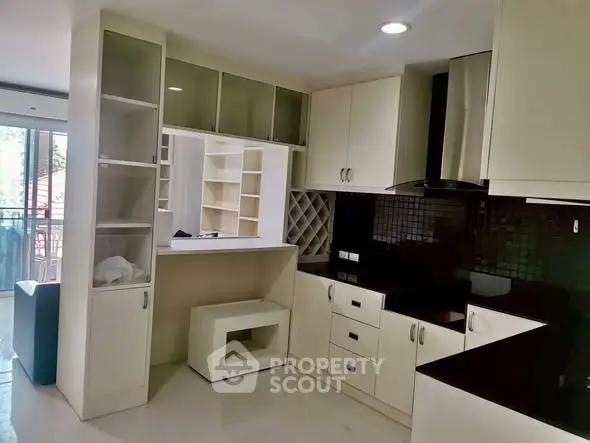 Modern kitchen with sleek cabinetry and open layout, featuring black countertops and ample storage.