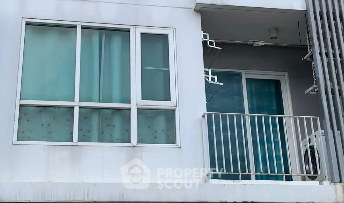 Modern apartment exterior with balcony and large windows, showcasing urban living.