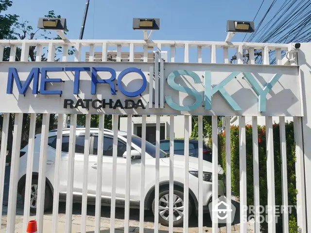 Modern Metro Sky Ratchada entrance with sleek design and white car parked outside.