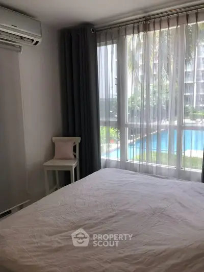 Cozy bedroom with pool view, featuring large window and air conditioning, perfect for relaxation.