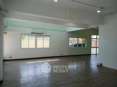 Spacious empty room with large windows and wooden flooring, ideal for customization.