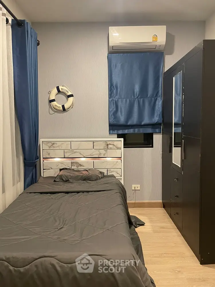 Cozy bedroom with modern design, featuring a comfortable bed, sleek furniture, and air conditioning, perfect for restful nights in a compact urban apartment.