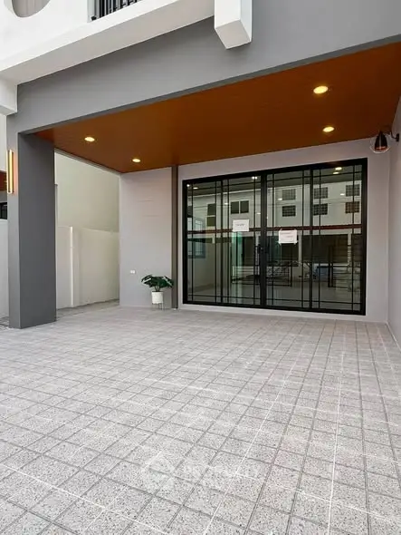 Modern building entrance with large glass doors and tiled flooring, ideal for commercial or residential use.