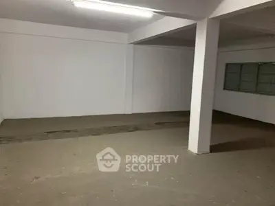 Spacious empty room with concrete floor and white walls, ideal for storage or renovation.