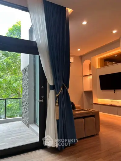 Luxurious living room with floor-to-ceiling windows and elegant curtains overlooking a serene balcony view.