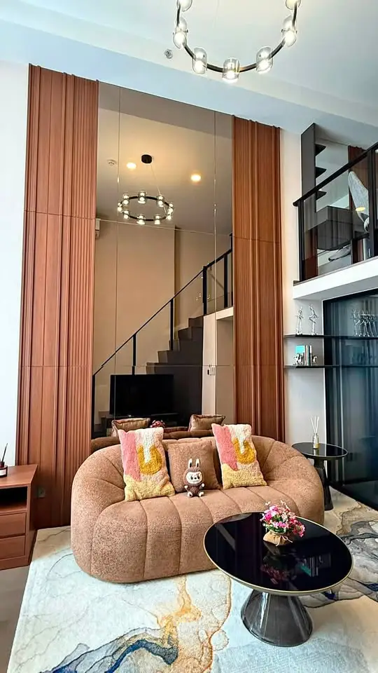 Luxurious modern living room with high ceilings, elegant staircase, and stylish furniture.
