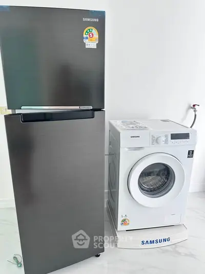 Modern kitchen appliances including a sleek fridge and washing machine in a bright interior.