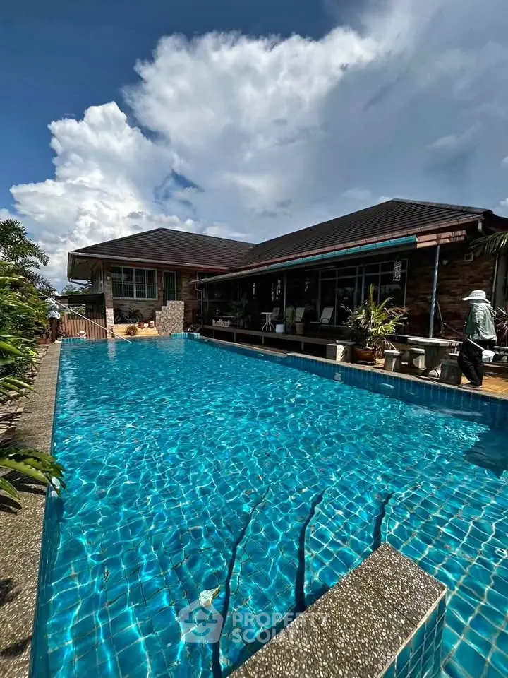 Luxurious home with stunning pool and spacious outdoor area under a clear blue sky.