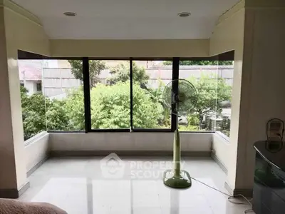 Spacious room with large windows offering lush garden views, perfect for relaxation and natural light.