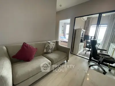 Modern living room with stylish sofa and open view to bedroom and study area.