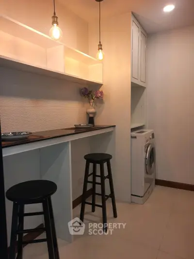 Modern kitchen nook with washing machine and stylish lighting