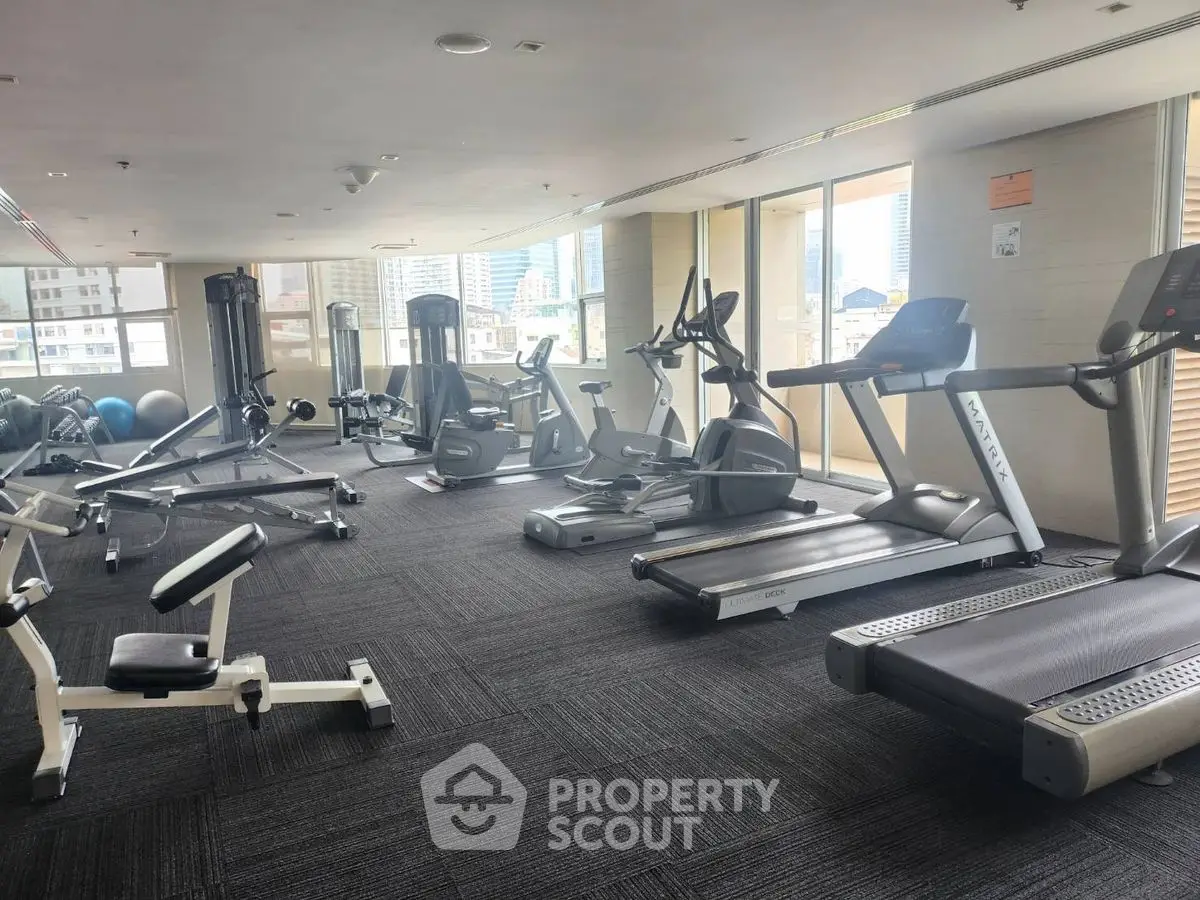 Spacious gym with modern fitness equipment and city view, perfect for active lifestyle enthusiasts.