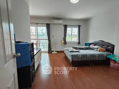 Spacious bedroom with wooden flooring and large windows for natural light