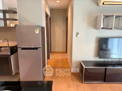 Modern apartment interior with sleek kitchen and cozy living area featuring wooden flooring and contemporary furniture.