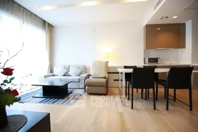 Modern living room with open kitchen, stylish furniture, and natural light.