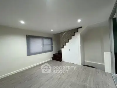 Spacious modern living room with staircase and large window, perfect for family gatherings.