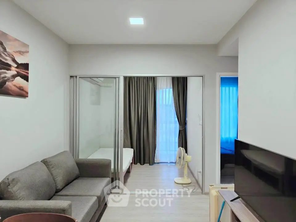 Modern living room with cozy sofa and sliding glass doors leading to a bedroom, featuring elegant decor.