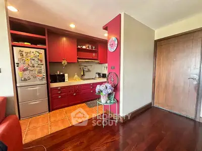 Charming kitchen with vibrant red cabinets and cozy wooden flooring, perfect for modern living.