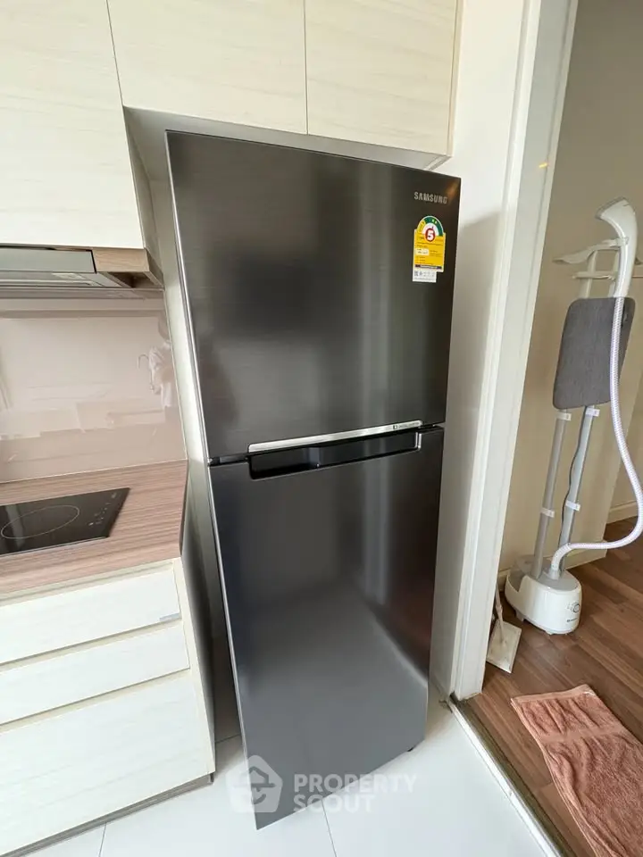 Modern kitchen with sleek stainless steel fridge and induction cooktop in stylish apartment.