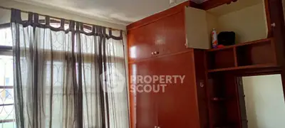 Spacious bedroom with large window and built-in wooden wardrobe