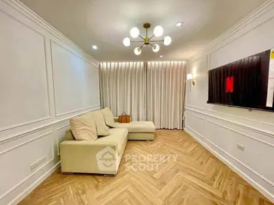 Elegant living room with modern chandelier and cozy beige sofa, featuring a wall-mounted TV and stylish wood flooring.