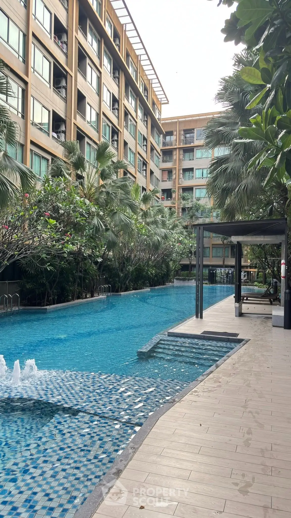 Luxurious condominium with stunning poolside view and lush greenery.
