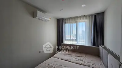 Cozy bedroom with air conditioning and large window offering city views.