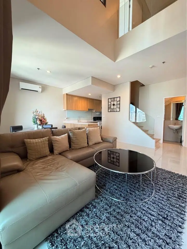 Spacious modern living room with open kitchen and stylish decor in a duplex apartment.