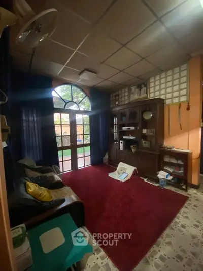 Cozy living room with large window and classic wooden furniture, perfect for relaxation and family gatherings.