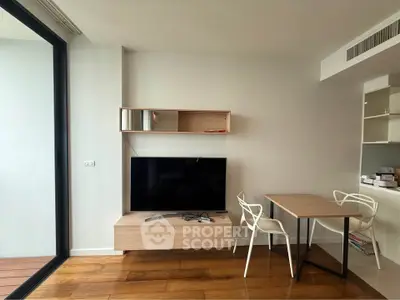 Modern living room with sleek furniture and large TV, featuring wooden flooring and a stylish open layout.