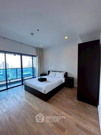 Spacious bedroom with city view and large balcony access in modern apartment