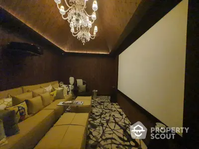 Luxurious home theater with plush seating and elegant chandelier lighting.