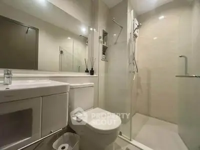 Modern bathroom with glass shower and sleek fixtures in contemporary apartment.