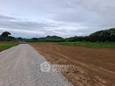 Expansive land plot with gravel road and lush greenery, ideal for development opportunities.