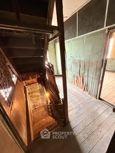 Explore this unique fixer-upper with vintage charm and potential, featuring rustic wooden floors and staircase.