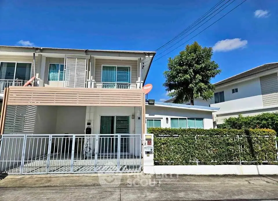 Modern two-story house with gated driveway and lush greenery in a serene neighborhood.