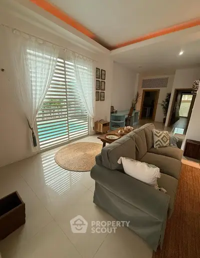 Spacious living room with modern decor and large window offering natural light.