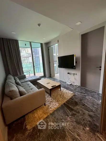 Modern living room with sleek design and balcony view, featuring a comfortable sofa and wall-mounted TV.