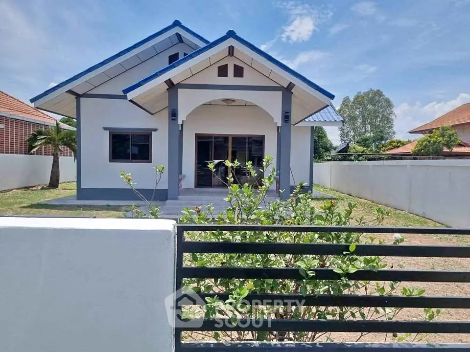 Charming single-story house with blue roof and spacious front yard in a serene neighborhood.