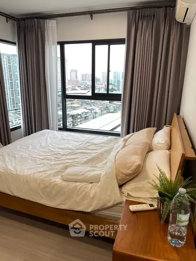 Modern bedroom with city view, featuring a cozy bed and large windows for natural light.