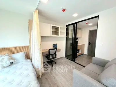 Modern studio apartment with sleek design, featuring a cozy bed, workspace, and compact kitchen area.