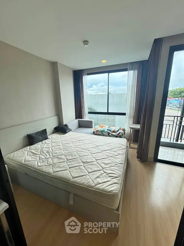 Cozy bedroom with large window and balcony access, featuring a comfortable bed and modern decor.