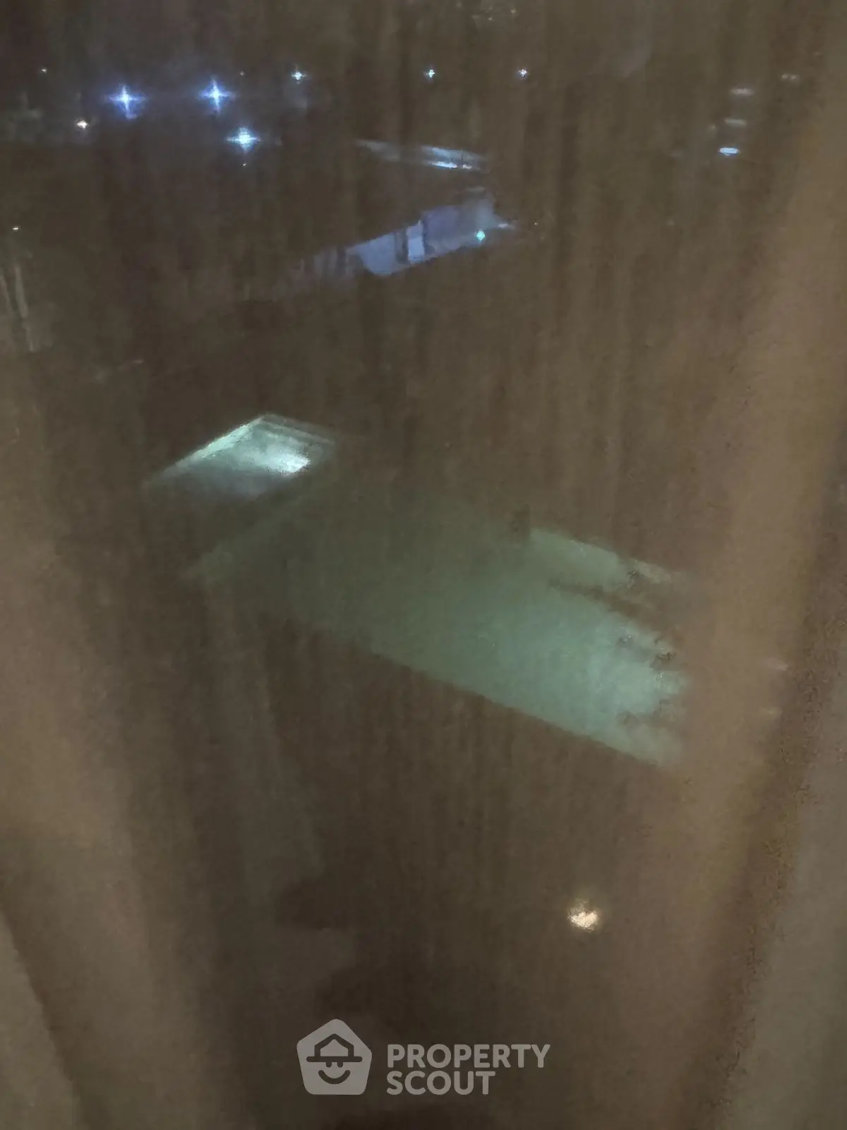 Night view of illuminated swimming pool through a window, offering a serene and inviting ambiance.