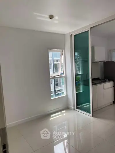 Modern apartment interior with sleek kitchen and sliding glass door, offering a bright and airy atmosphere.