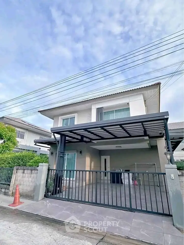Modern two-story house with gated driveway and contemporary design in a suburban neighborhood.
