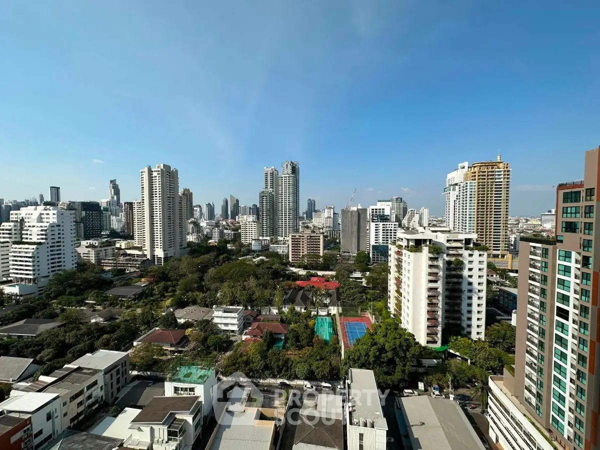 Stunning cityscape view showcasing modern high-rise buildings and lush greenery under a clear blue sky.